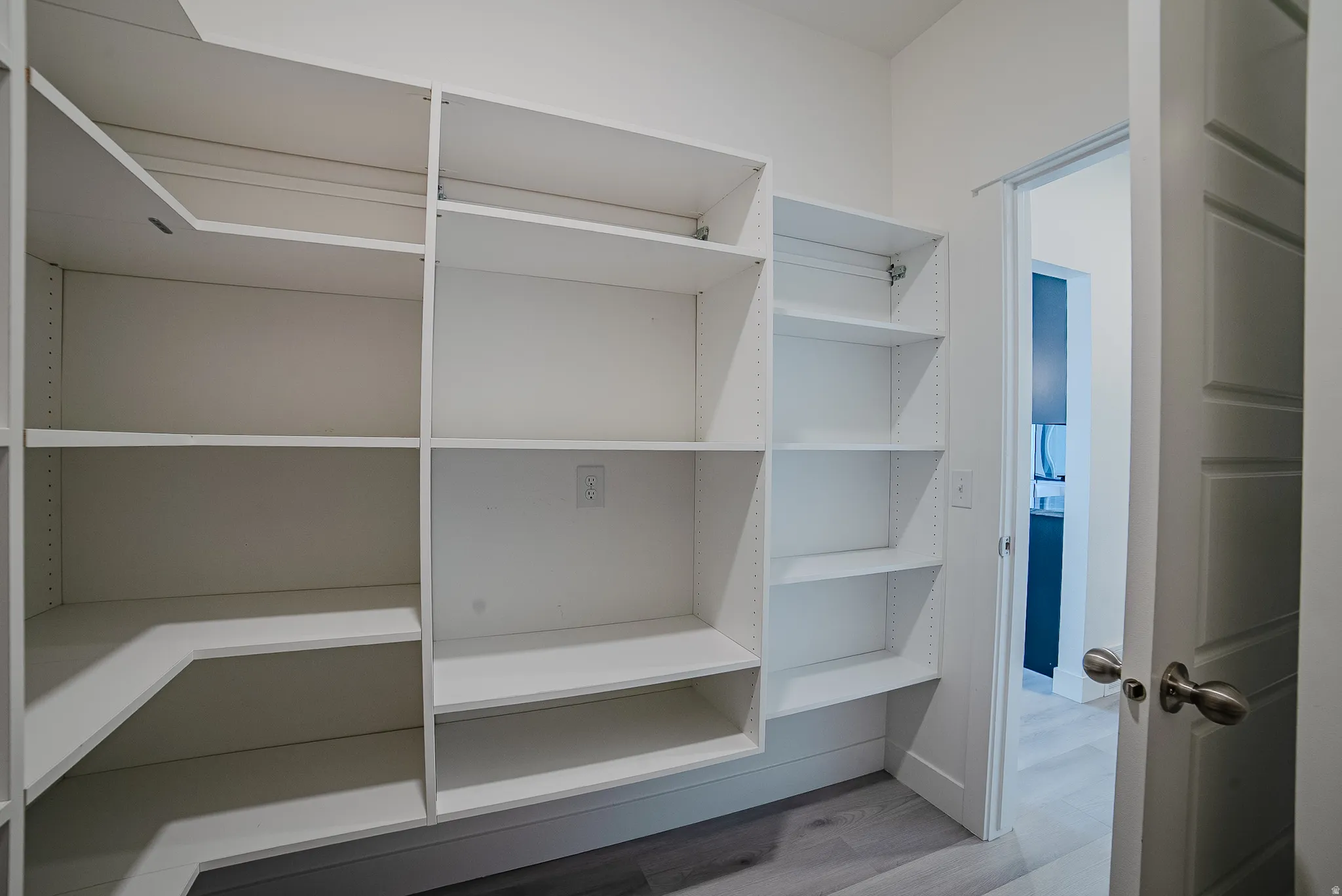 Custom white built-in shelving system with adjustable shelves, extending along two walls