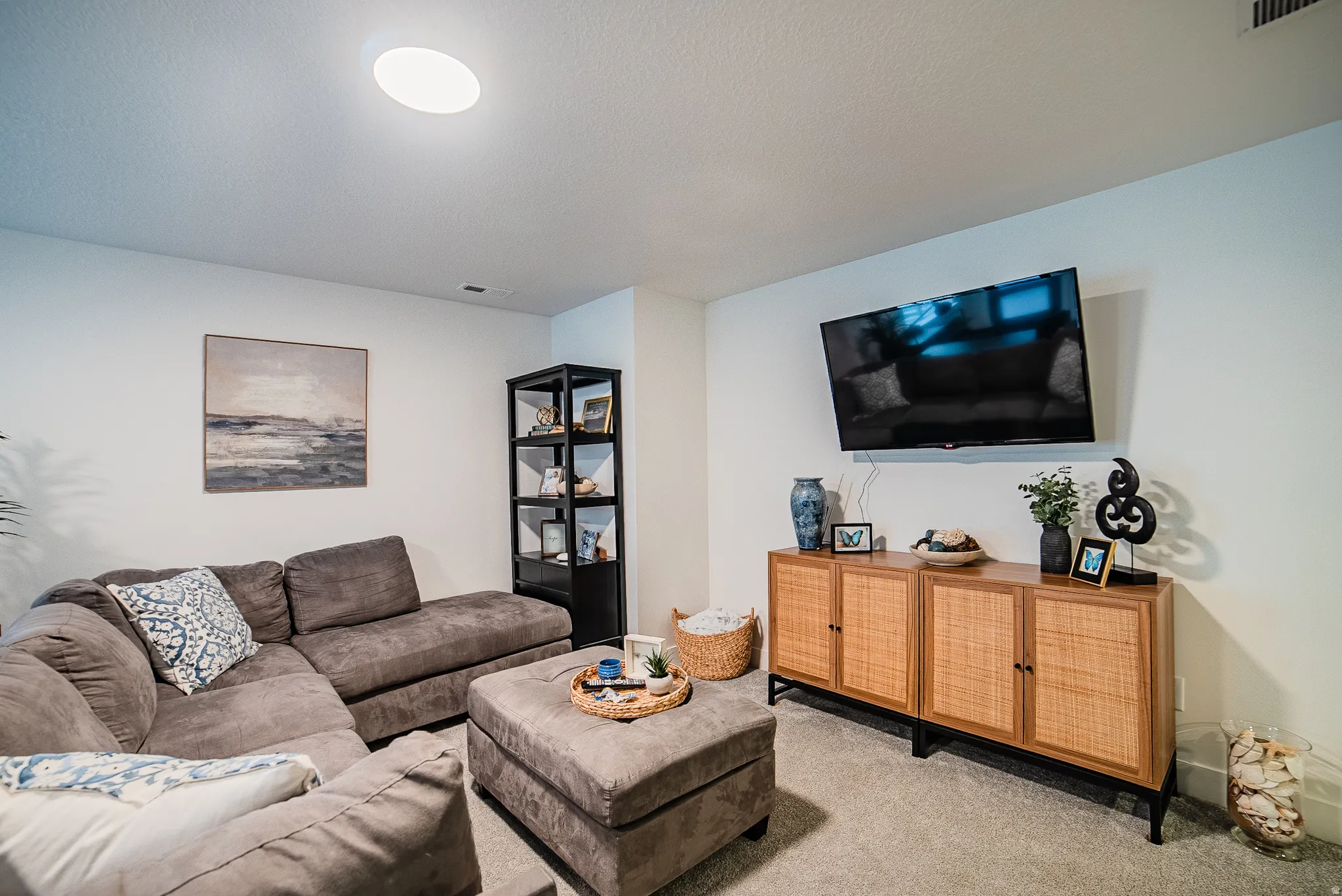Recessed ceiling lighting illuminates a room featuring light-toned walls and carpet flooring