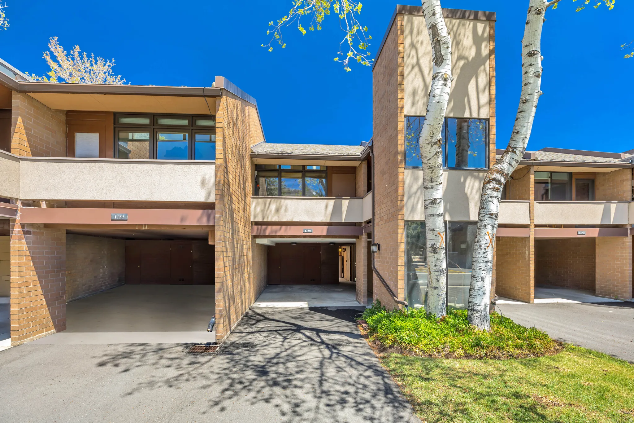 View of unit with carport and the balcony off of the primary bedroom