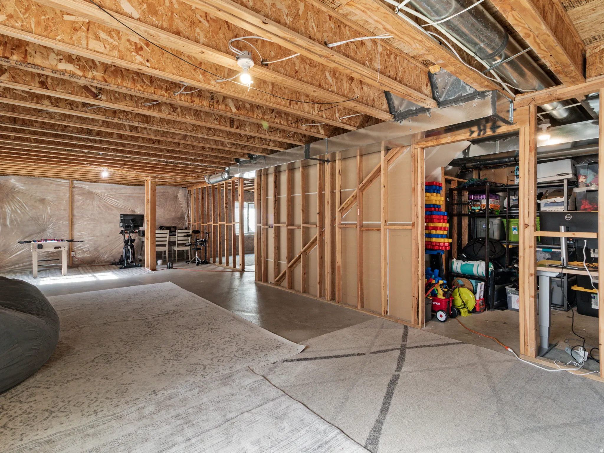 Unfinished basement featuring exposed wood joists, concrete flooring, and framed walls