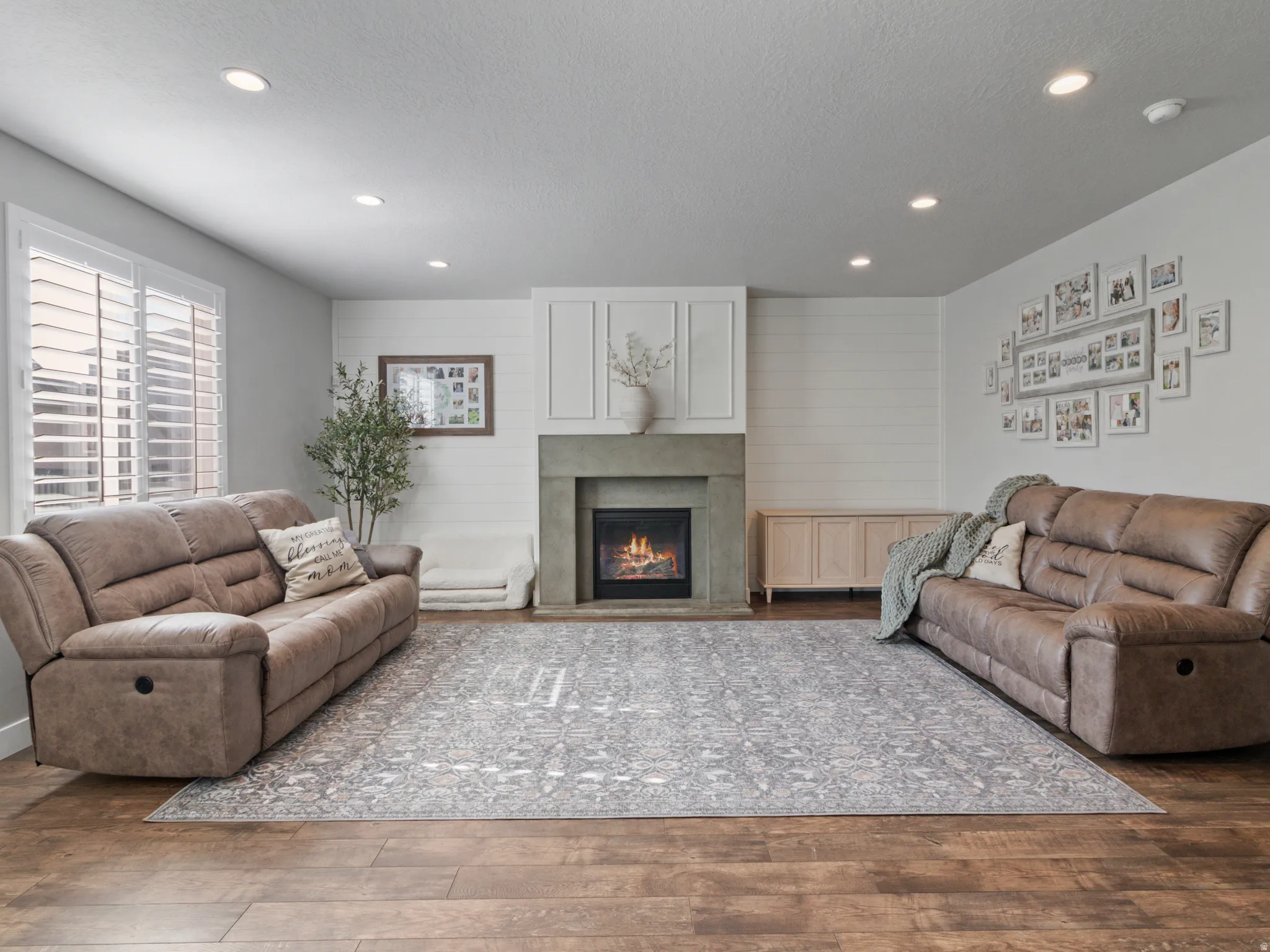 Living area featuring wood-finish flooring, recessed lighting, and a fireplace with a concrete-style hearth and mantle