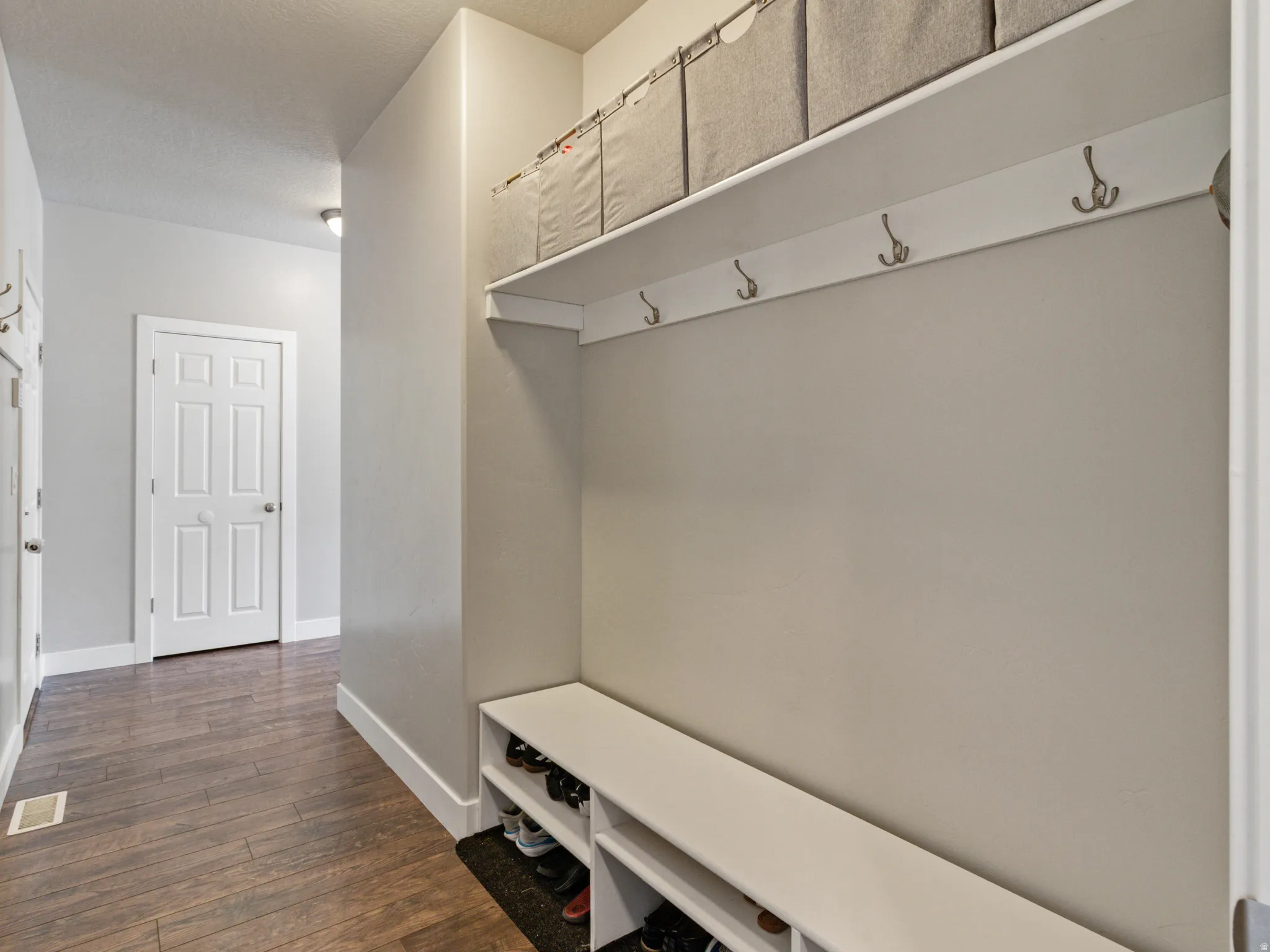 Entryway featuring wood-finish flooring and a built-in storage bench with shoe cubbies