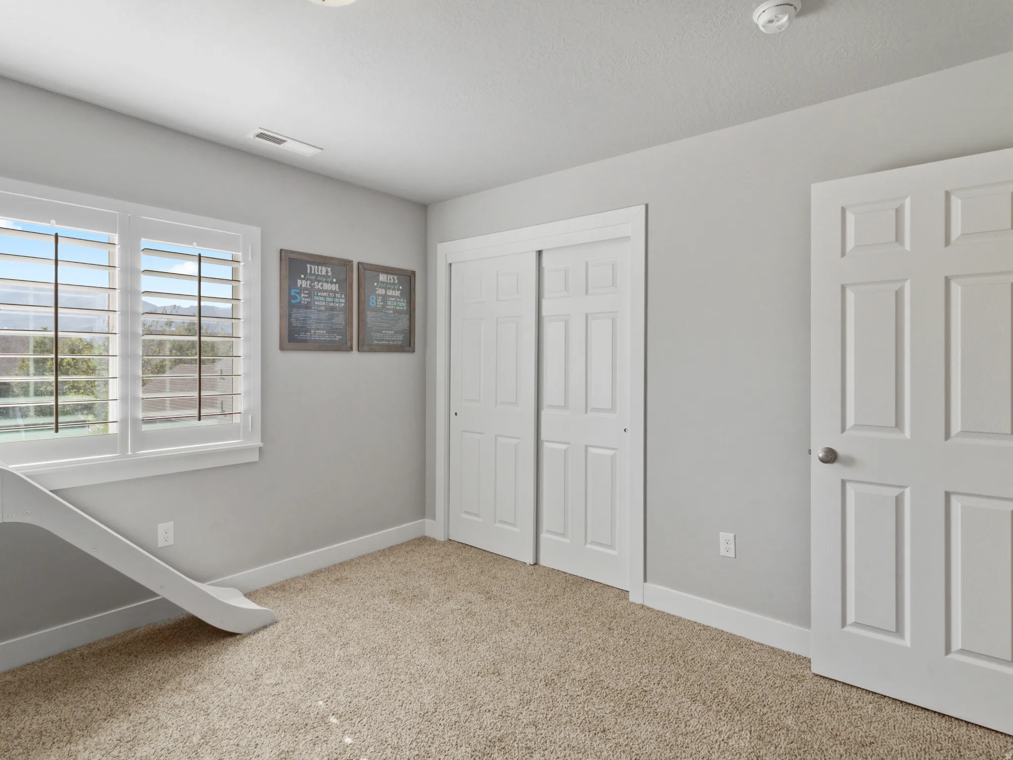 Room featuring neutral-toned carpet flooring, light gray walls, and white trim throughout