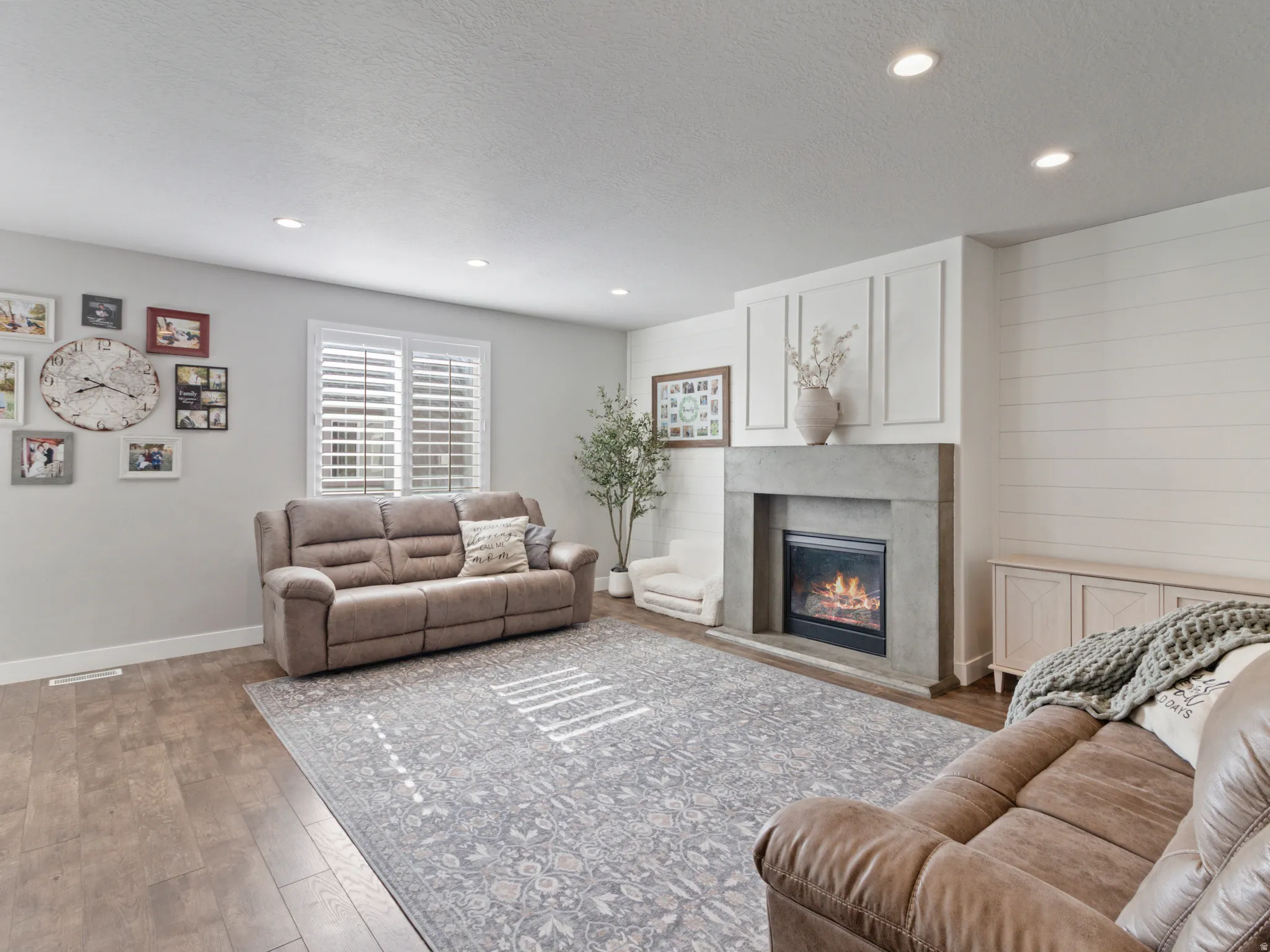 Open living space featuring wood-finish flooring, recessed lighting, and a window with plantation shutters