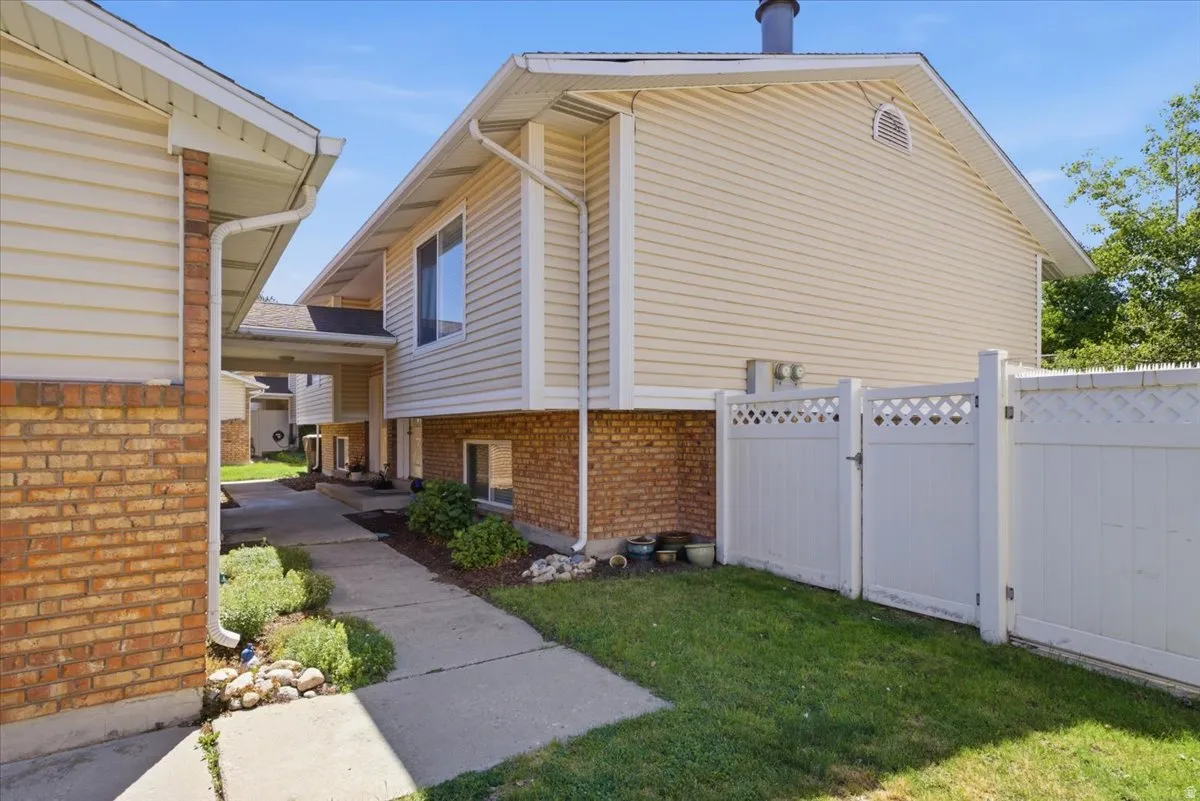 Exterior featuring tan siding, brick wainscoting, and white rain gutters