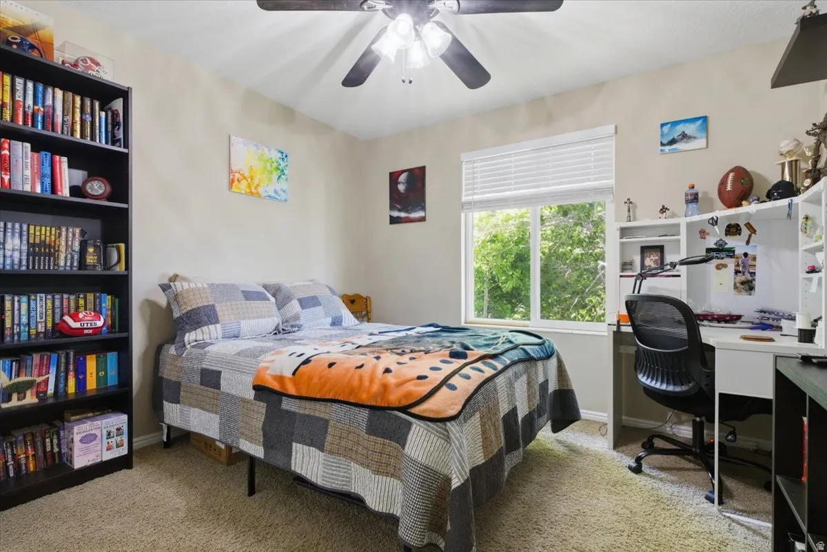 Bedroom featuring neutral wall paint, light-colored carpeting, a window with blinds, and a ceiling fan with integrated lighting