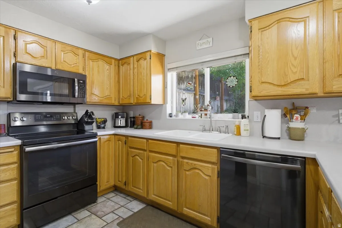 Kitchen featuring light wood cabinetry with arch panel doors and light countertops