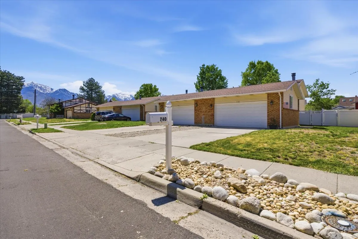 Duplex property featuring brick and siding exterior, a two-car garage, and a gravel and rock landscaping element