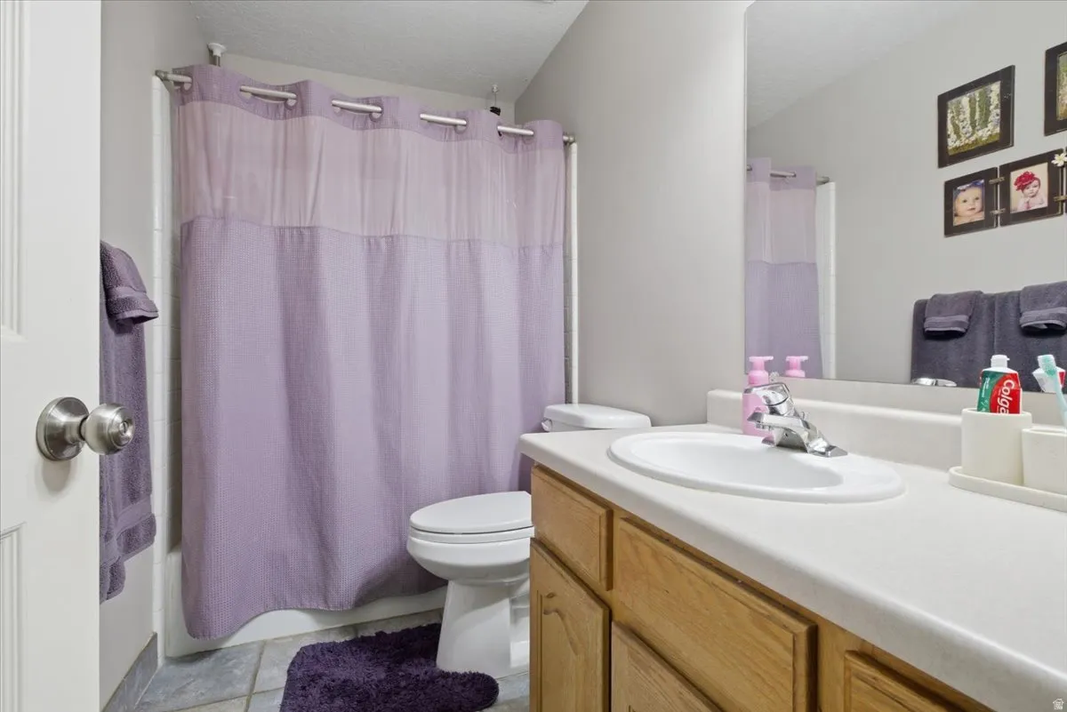 Full bathroom featuring a single vanity with wood-finish cabinetry, a white countertop, and an integrated sink