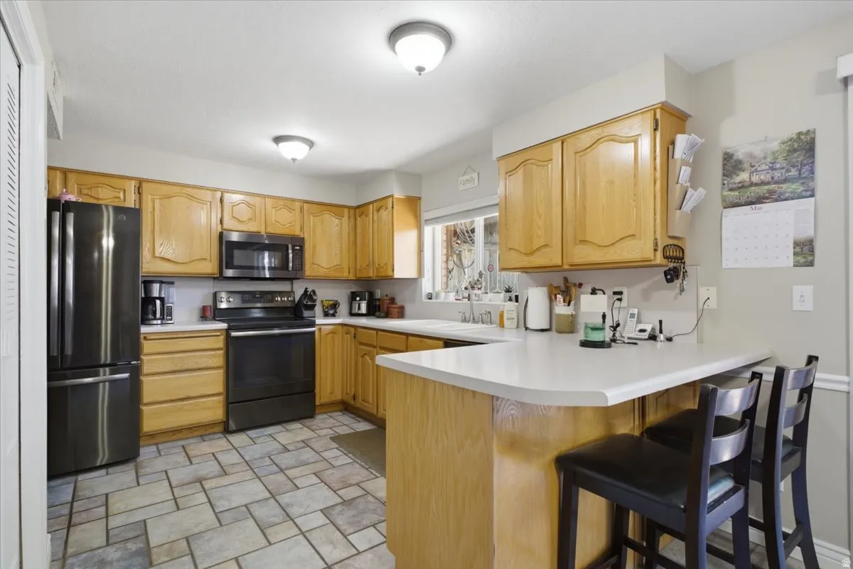 Kitchen featuring light wood cabinetry, white countertops, and black stainless steel appliances