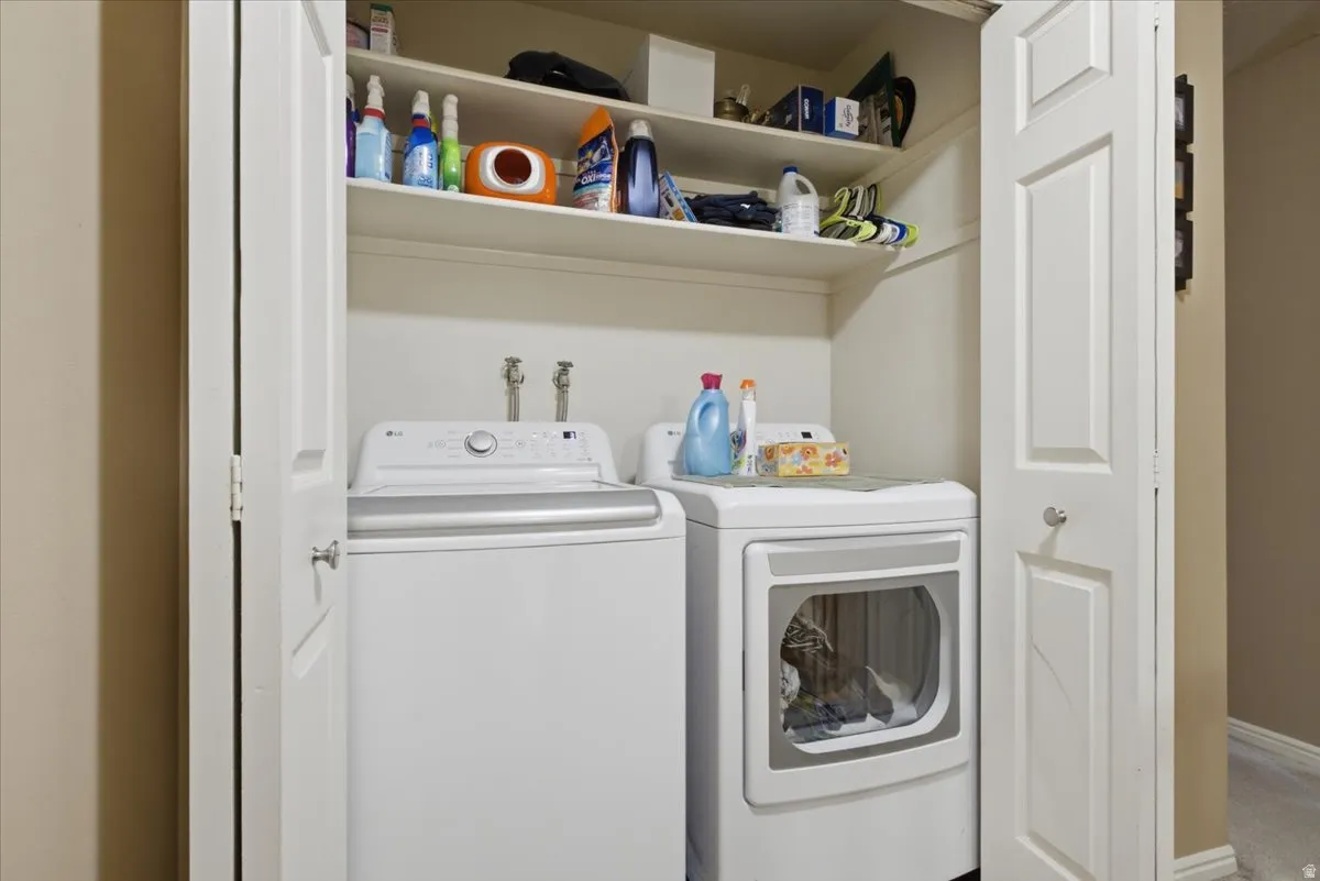 Dedicated laundry alcove featuring bi-fold doors, upper shelving, and hookups for a washer and dryer