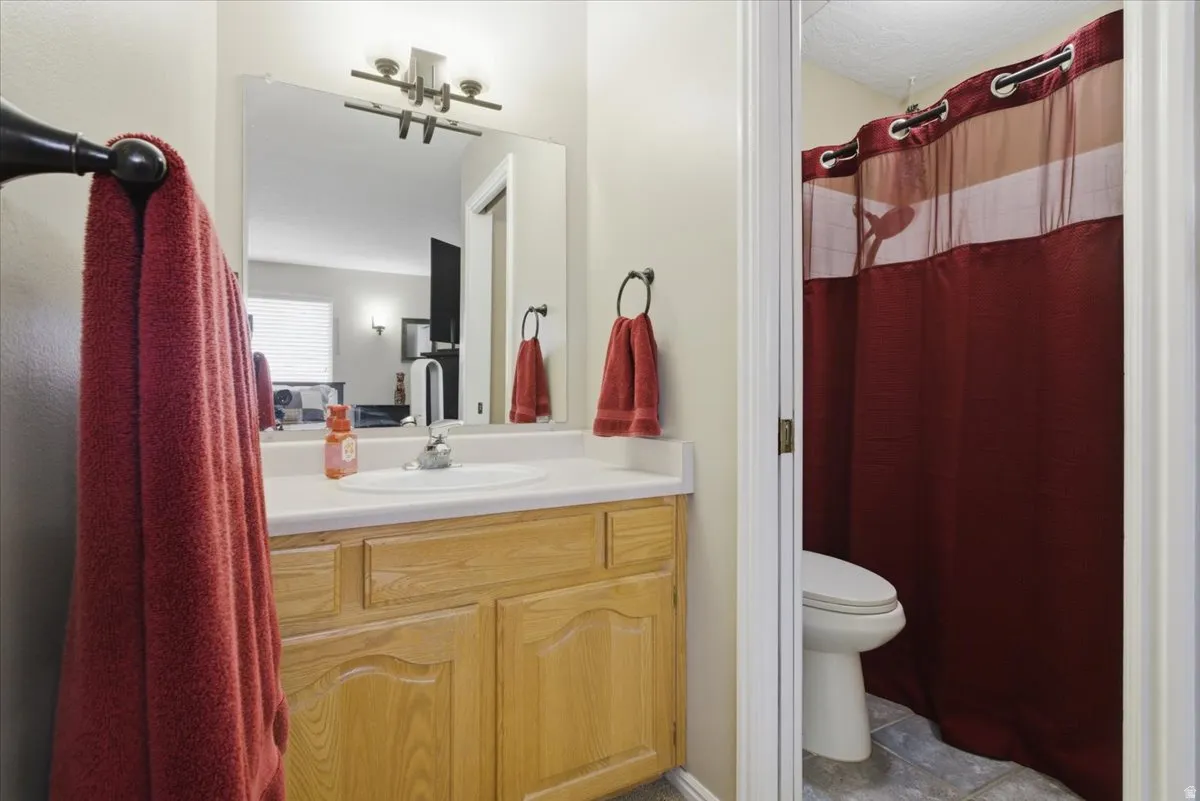 Bathroom featuring a single vanity with a laminate countertop, integrated sink, and light wood cabinetry