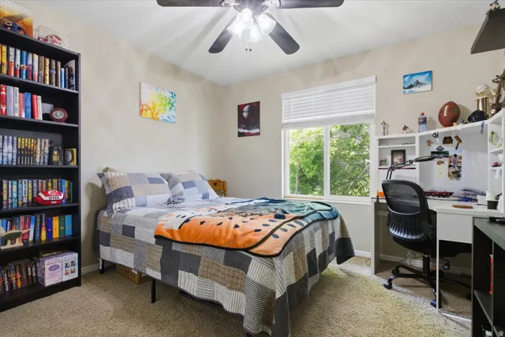 Bedroom featuring neutral wall paint, light-colored carpeting, a window with blinds, and a ceiling fan with integrated lighting