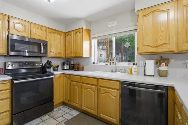 Kitchen featuring light wood cabinetry with arch panel doors and light countertops