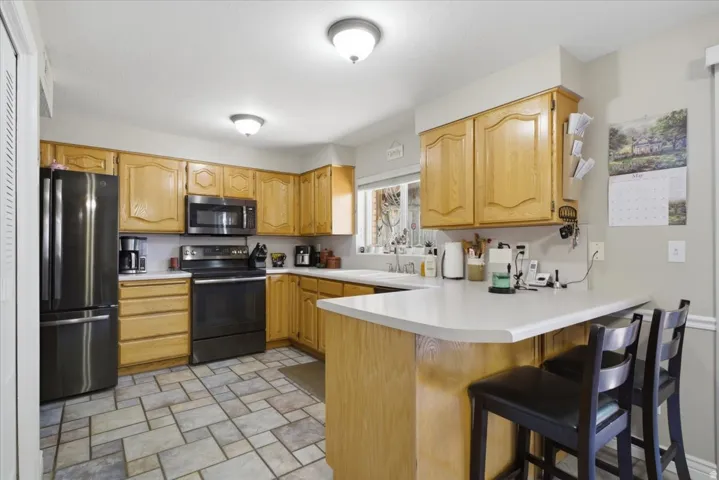 Kitchen featuring light wood cabinetry, white countertops, and black stainless steel appliances