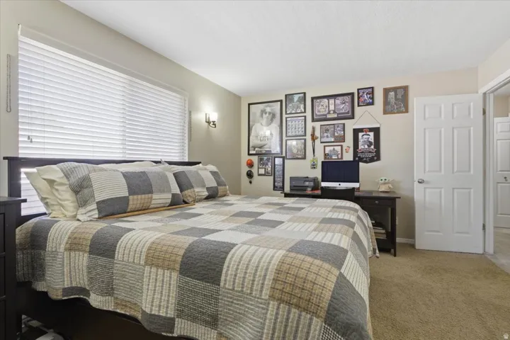 Bedroom featuring light beige wall paint, white horizontal blinds, and a white six-panel door