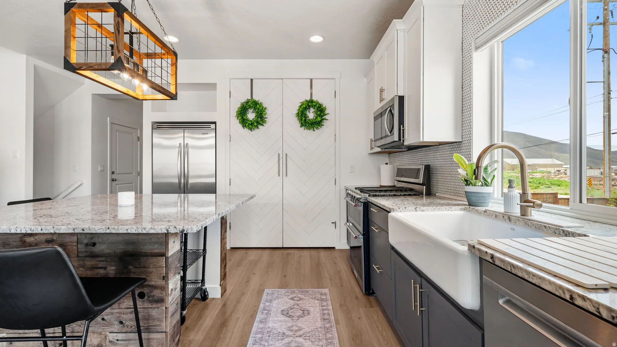 Kitchen featuring a deep farmhouse sink, two-tone cabinetry, and wood-finish flooring