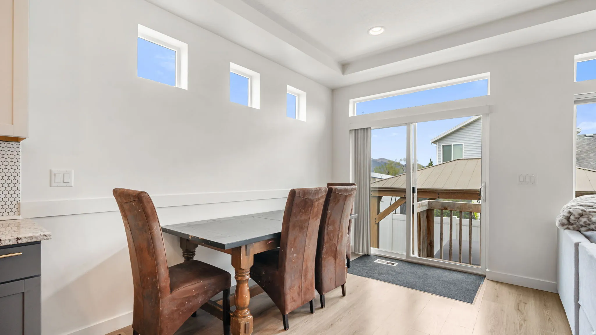 Dining area featuring light wood-finish flooring, white walls, and a sliding glass door leading to an outdoor deck