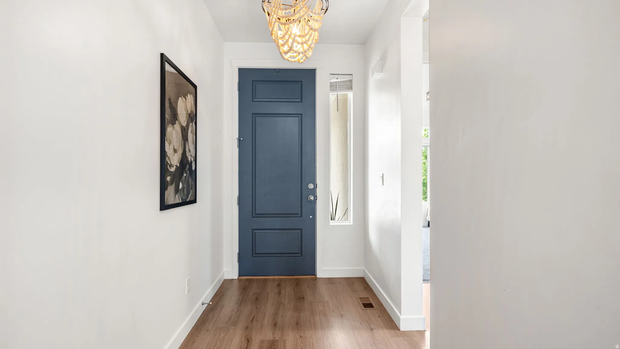 Entryway with a paneled door, wood-finish flooring, and a decorative light fixture