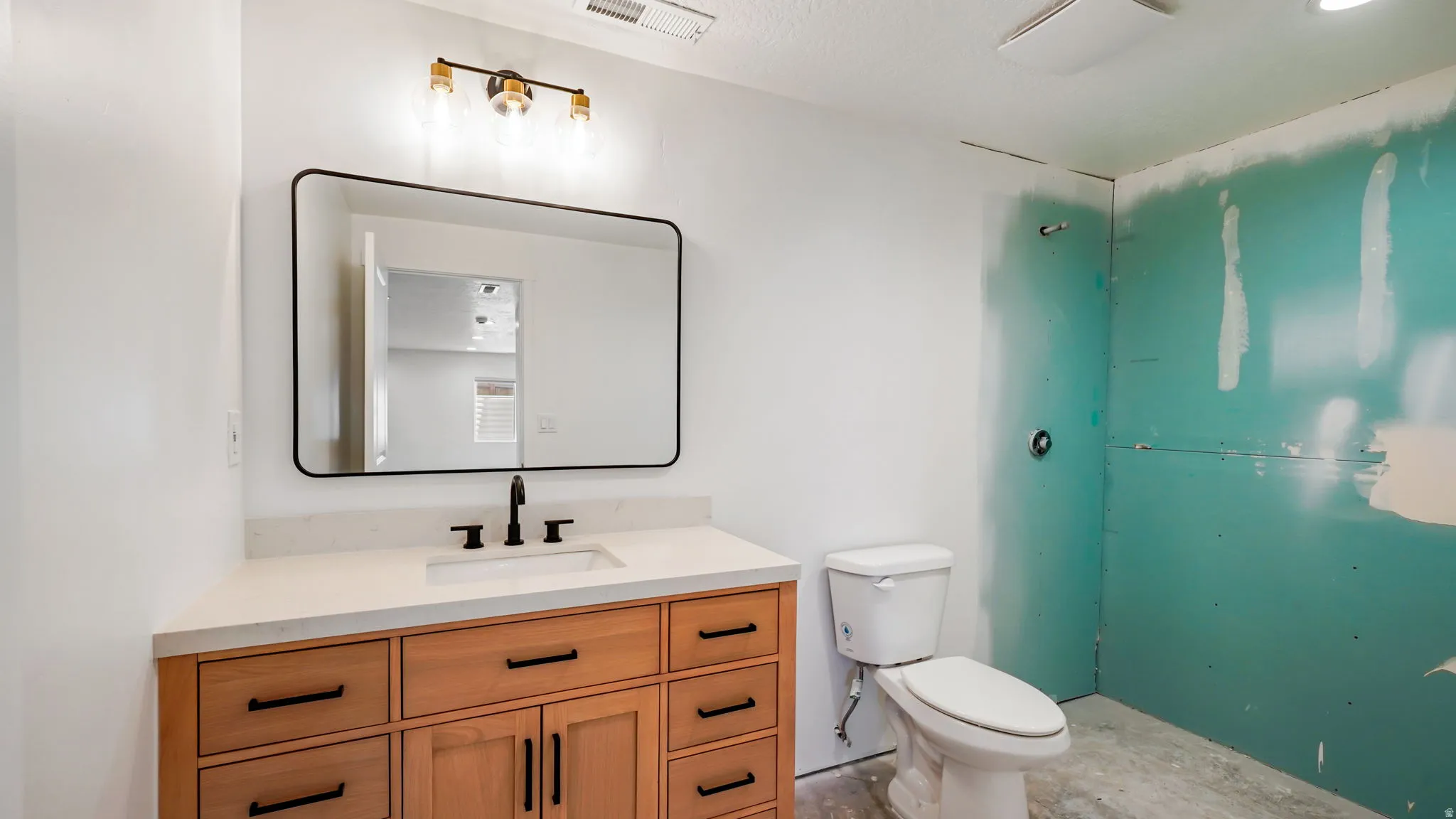 Bathroom featuring a light wood-finish vanity with quartz-style countertop, undermount sink, and matte black faucet