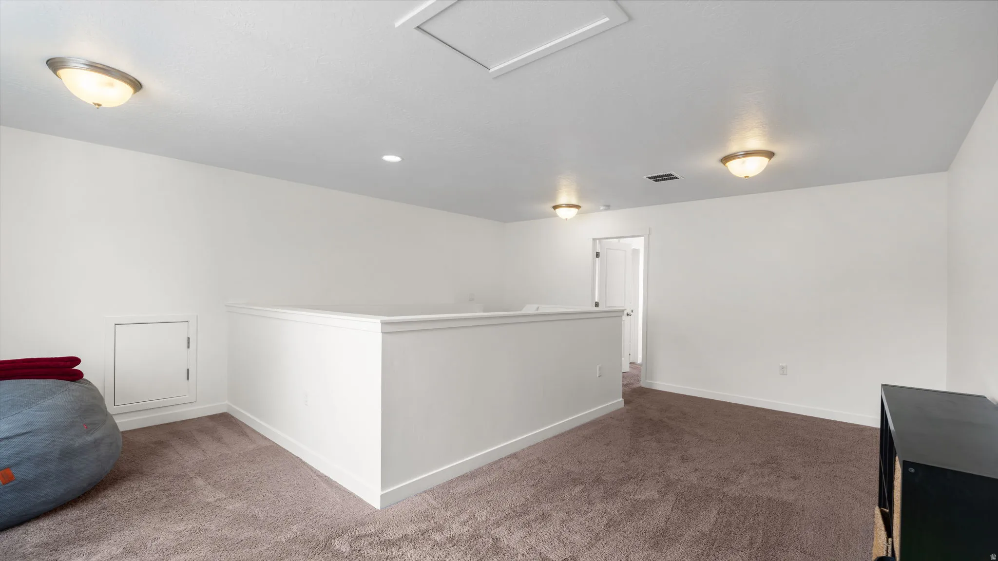 Spacious loft area featuring neutral carpeting and white wall finishes