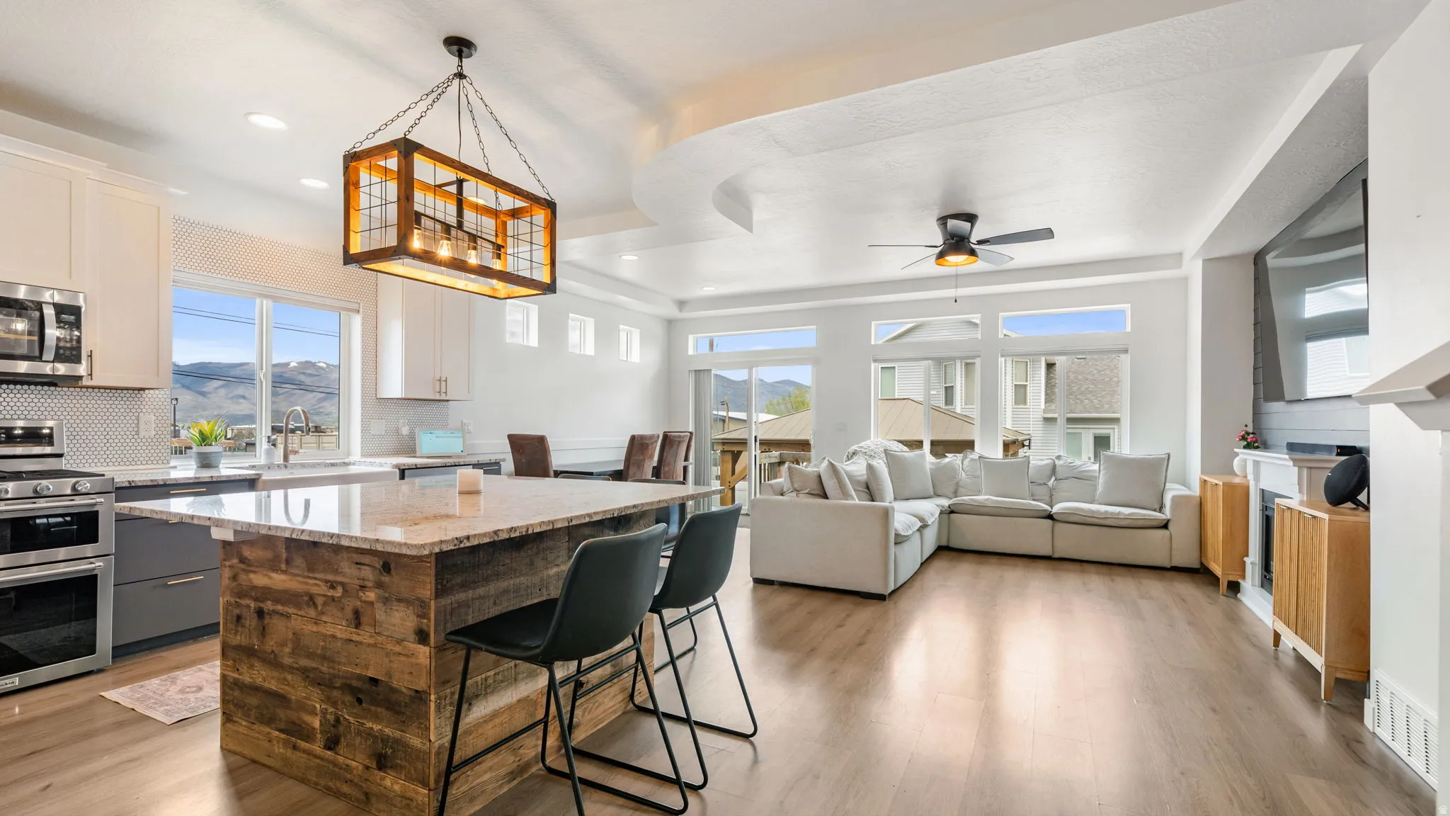 Open-concept living area featuring a kitchen with a wood-finish island, granite countertops, stainless steel appliances, and a tiled backsplash