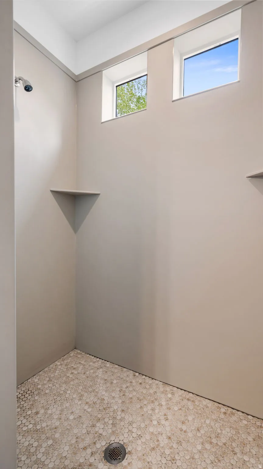 Master walk-in shower featuring a chrome showerhead, integrated corner shelf, and hexagonal tile flooring