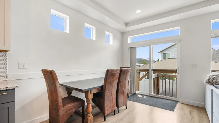 Dining area featuring light wood-finish flooring, white walls, and a sliding glass door leading to an outdoor deck