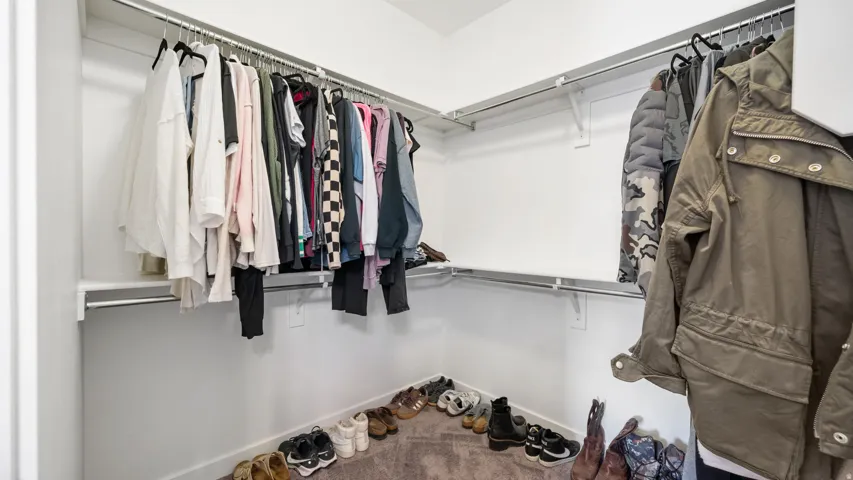 Master bedroom walk-in closet featuring built-in shelving and chrome hanging rods