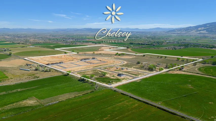 Expansive land parcel featuring new construction and established roadways, surrounded by green fields and distant mountains