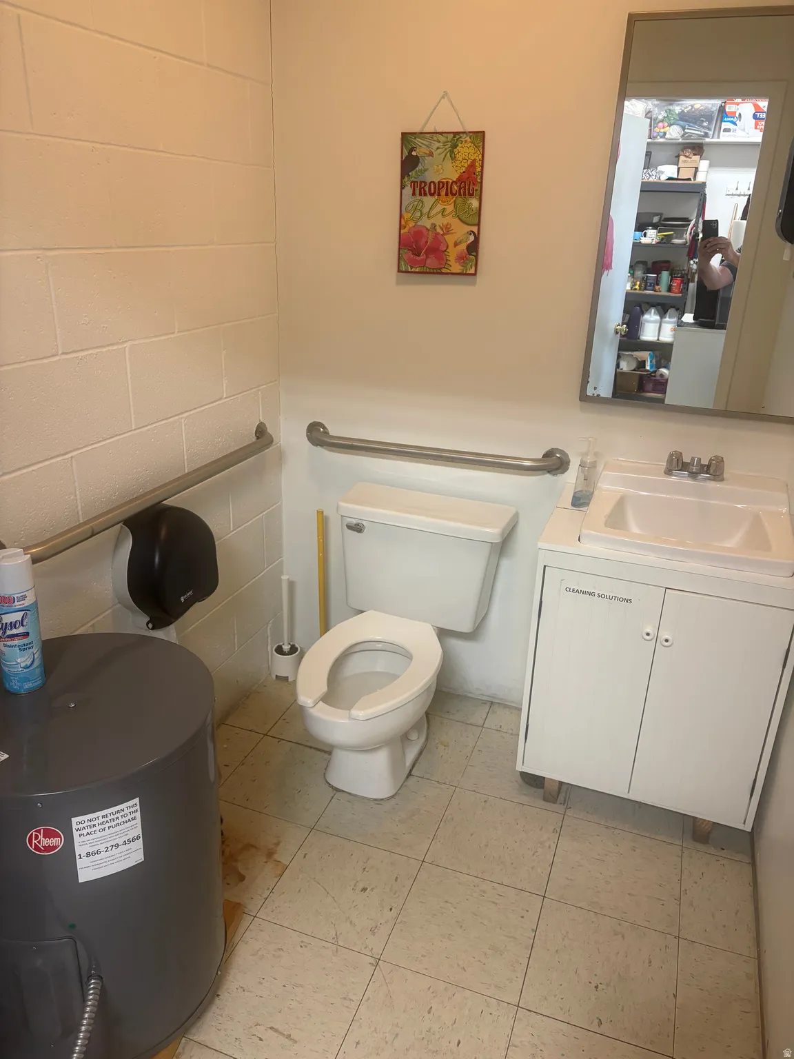 Restroom featuring a white toilet, wall-mounted sink with cabinet, and a large wall mirror