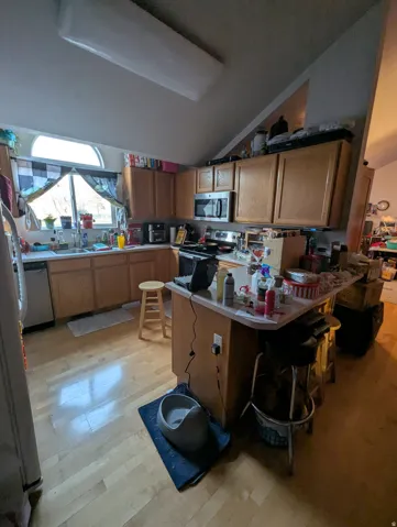 Kitchen featuring wood-finish flooring, ample wood cabinetry, a built-in microwave, and a window above the sink