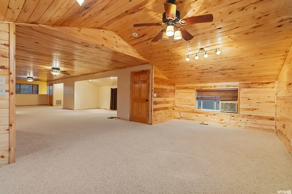 Bonus room with ceiling fan, wood walls, light carpet, and a vaulted wood ceiling