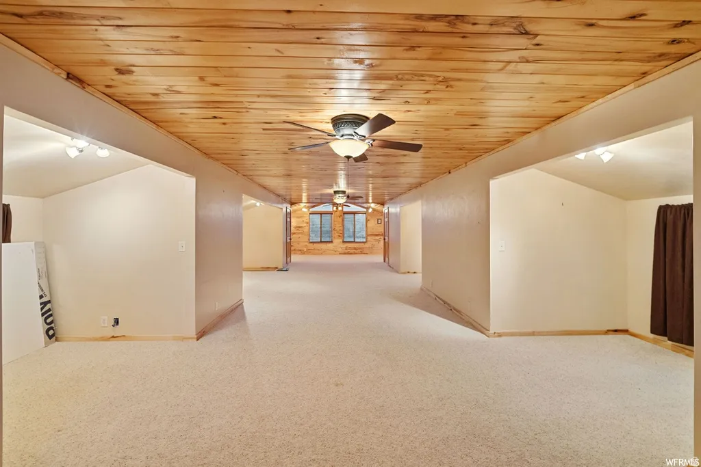 Bonus room with ceiling fan, wood ceiling, and light colored carpet