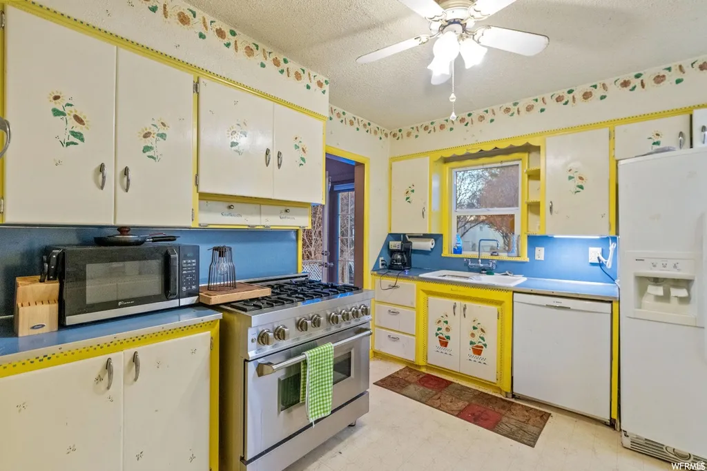 Kitchen featuring light flooring, white appliances, a ceiling fan, a textured ceiling, and ventilation hood