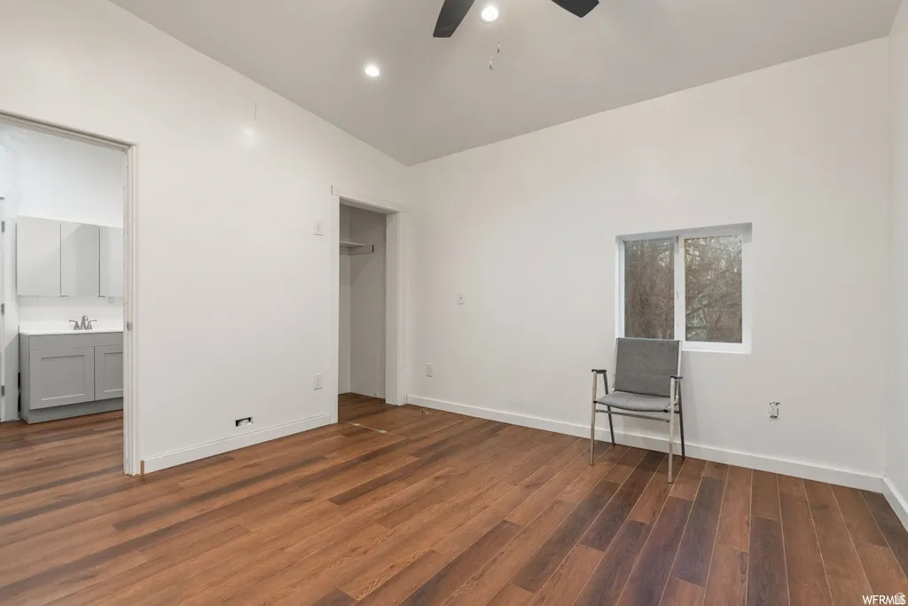 Unfurnished bedroom featuring dark wood-style floors, lofted ceiling, ceiling fan, and ensuite bathroom
