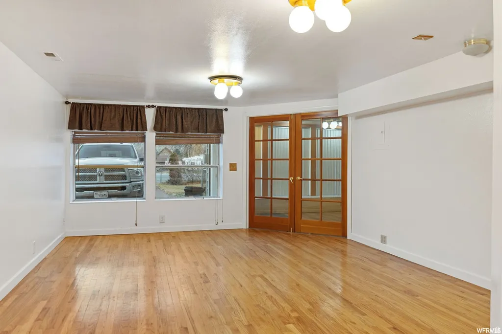 Empty room with french doors and light wood finished floors
