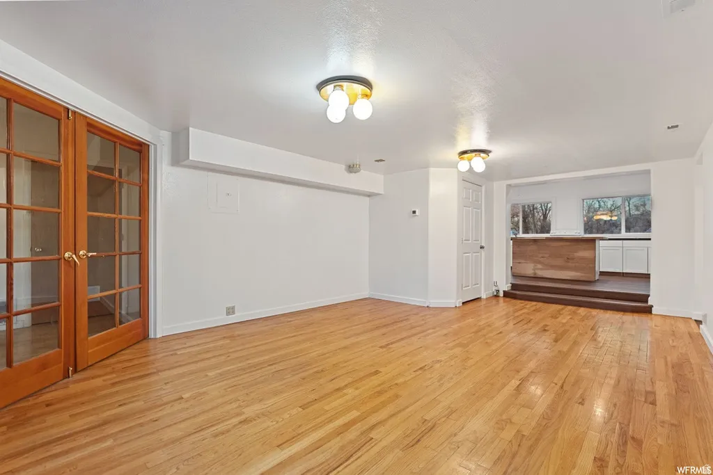 Unfurnished living room with light wood-style flooring and french doors