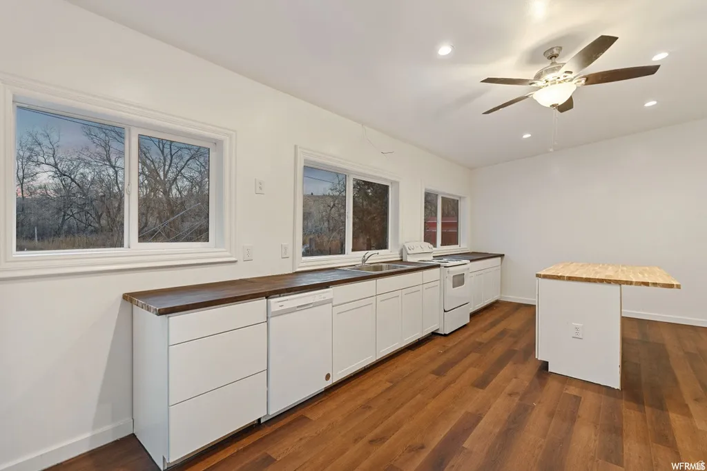 Kitchen with wood counters, white cabinetry, white appliances, dark wood-type flooring, and a center island