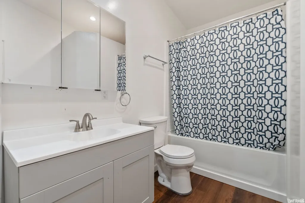 Full bath featuring vanity, shower / bath combo, and dark wood-type flooring