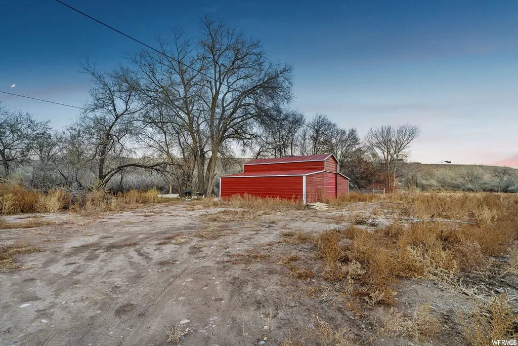 Yard at dusk featuring an outbuilding and a rural view