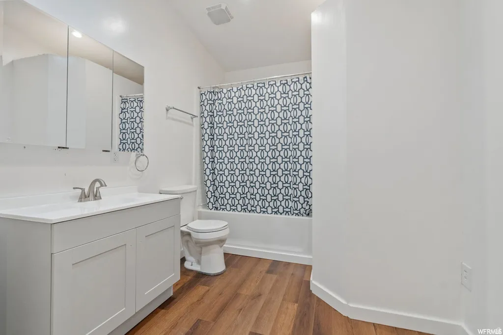 Full bathroom with vanity, dark wood-style floors, and shower / bath combination with curtain