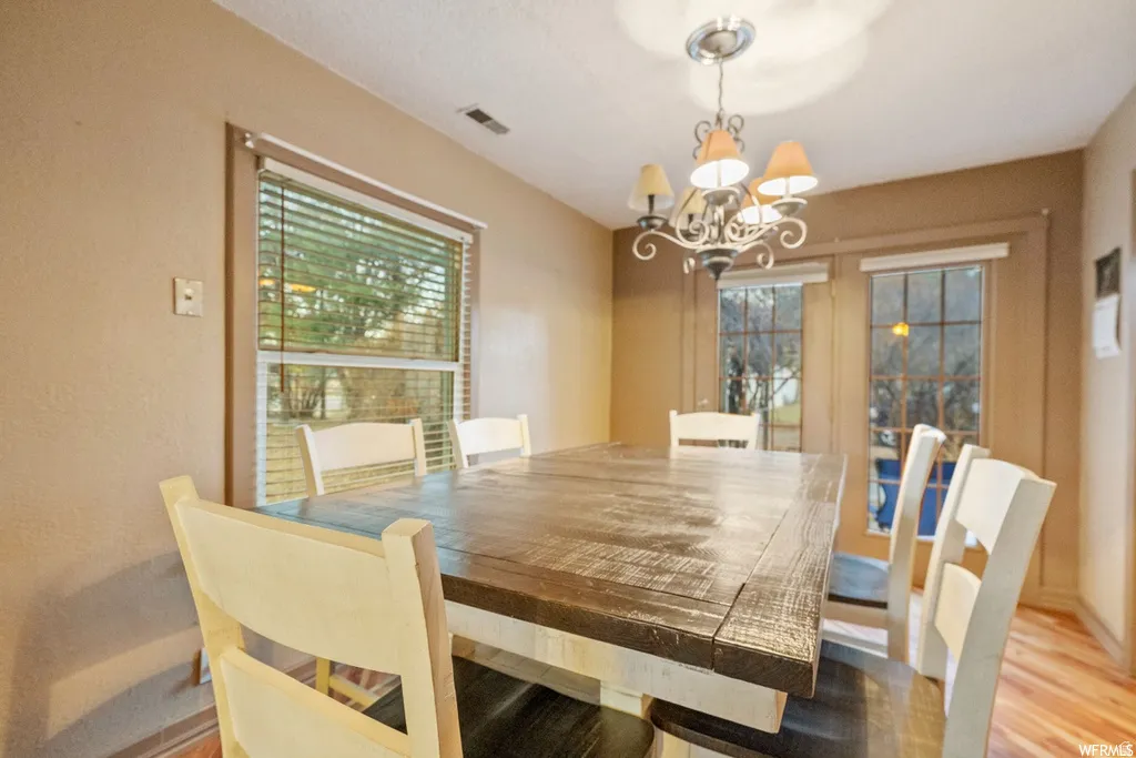 Dining space with suspended lighting and light wood-type flooring