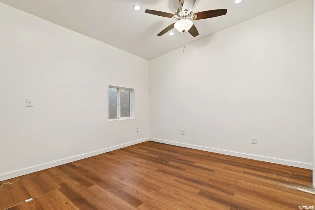 Unfurnished room featuring wood finished floors, ceiling fan, vaulted ceiling, and recessed lighting