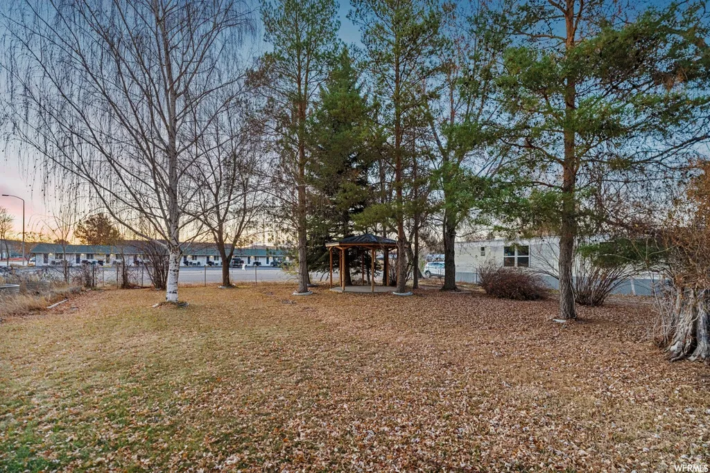 Yard at dusk featuring a gazebo, a patio area, and a lawn