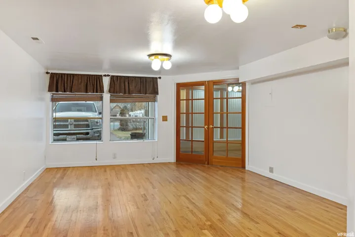 Empty room with french doors and light wood finished floors