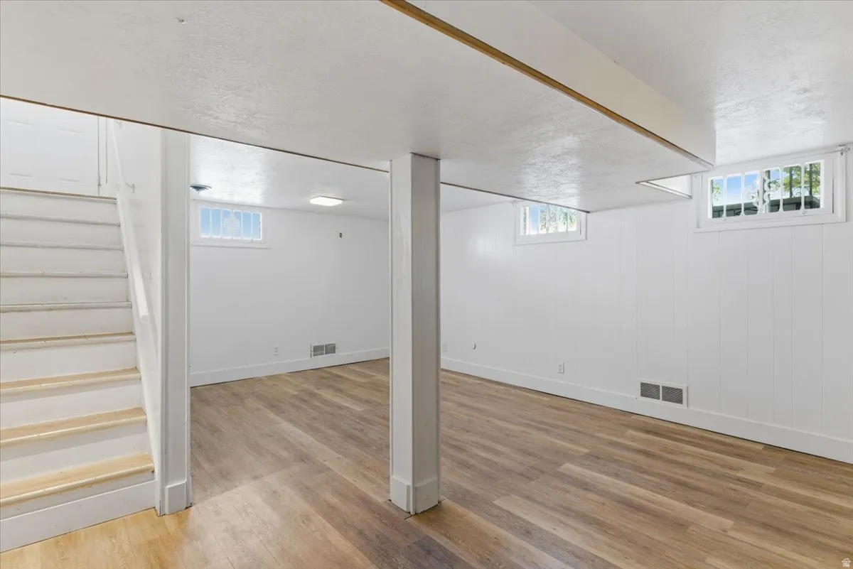 Spacious lower-level room featuring wood-finish flooring and white walls