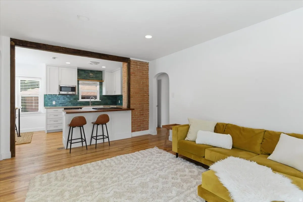 Open-concept living area with wood-finish flooring and an exposed brick accent wall