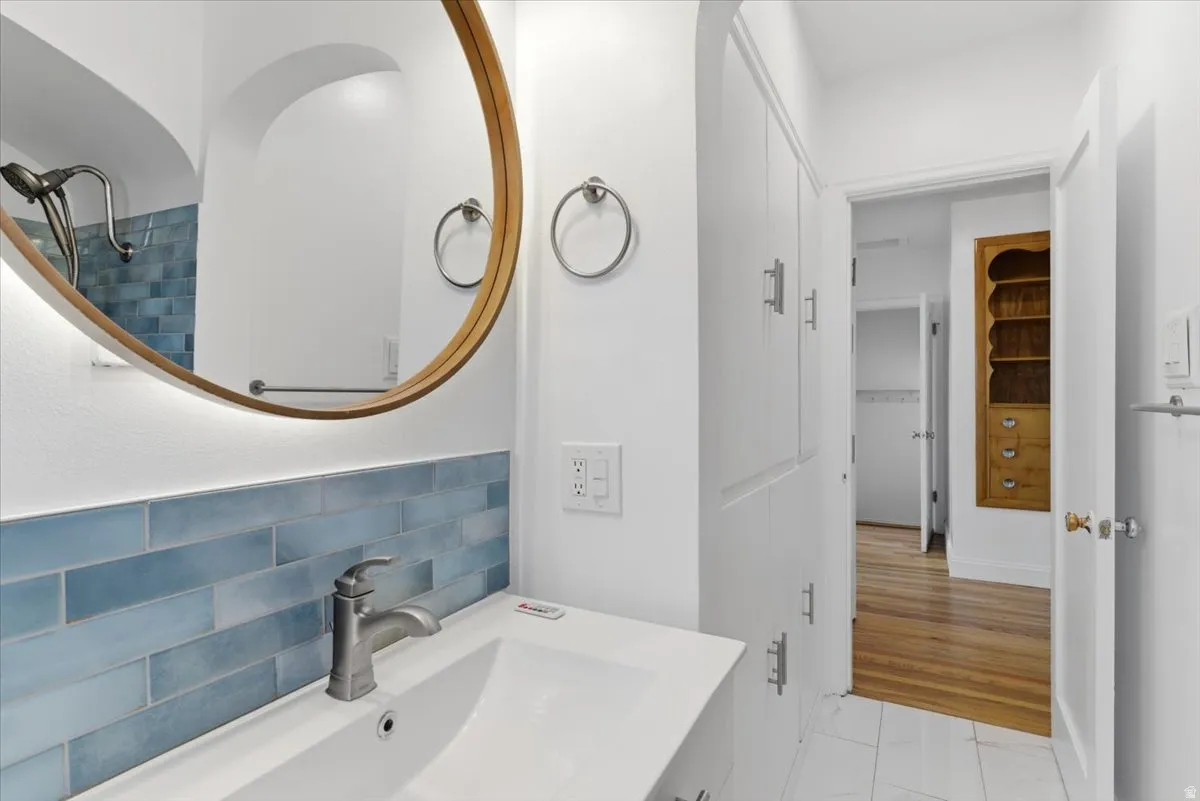 Bathroom vanity with white countertop and integrated sink, brushed nickel faucet, and blue subway tile backsplash