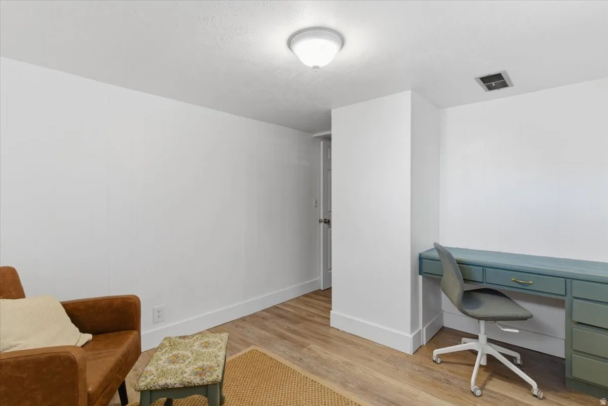 Room featuring wood-finish flooring, white walls, and a flush-mount ceiling light